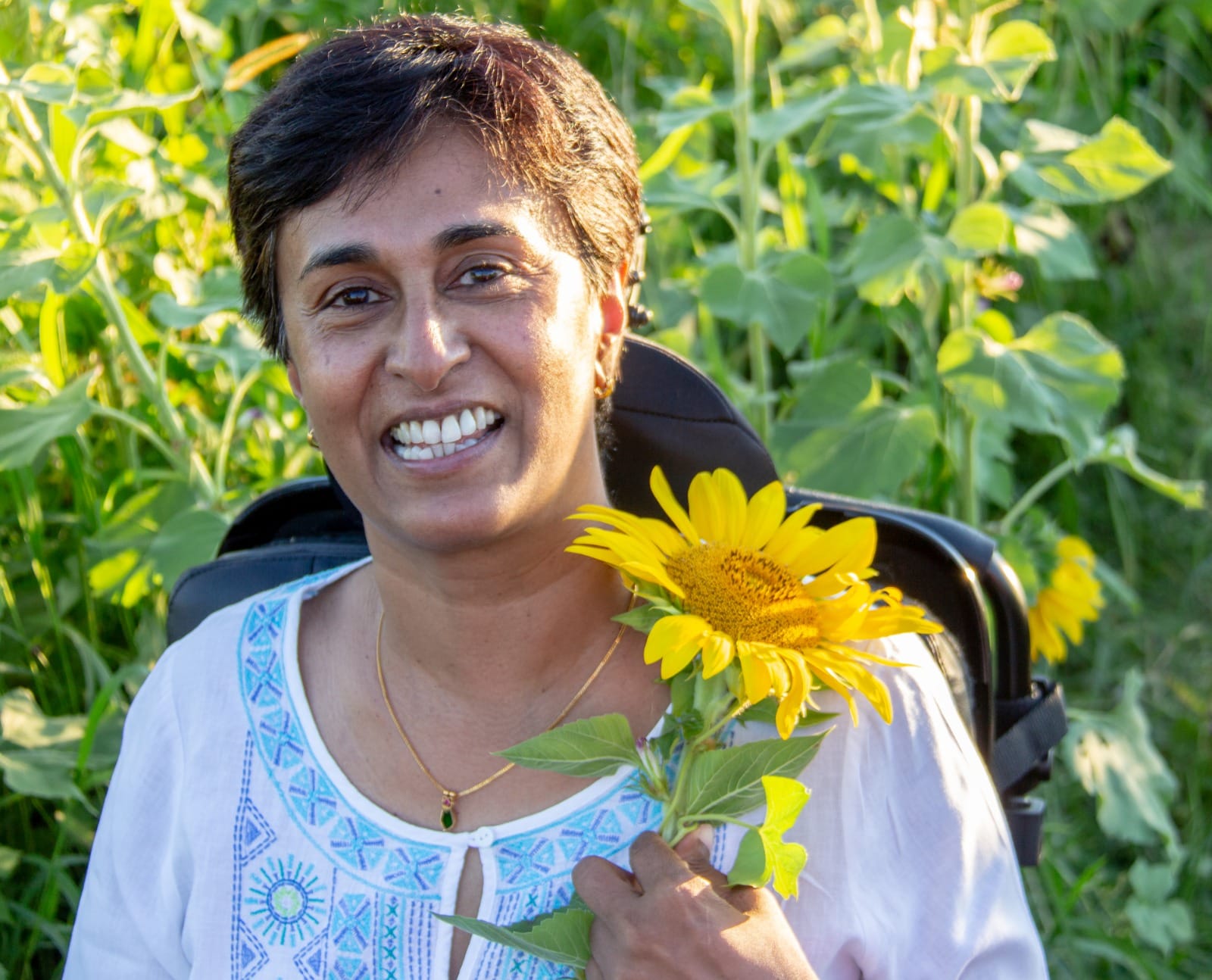 Chachie Joseph smiling and holding sunflowers